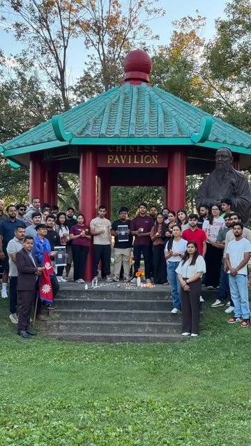 Community members standing together on the steps of a park pavilion on the evening of the vigil.